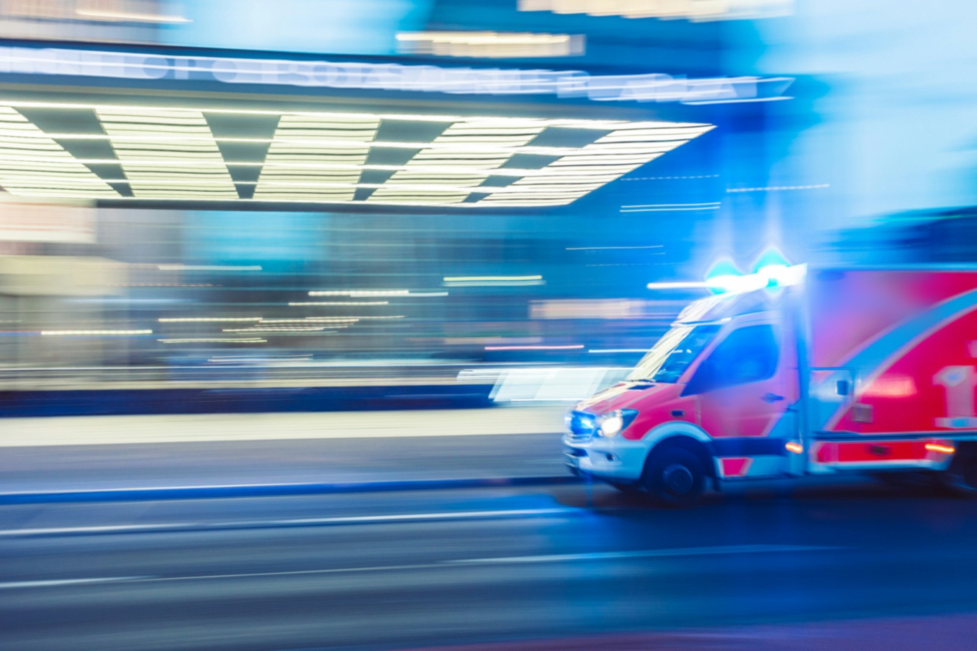 Rettungswagen mit eingeschaltetem Blaulicht in einer Nachtaufnahme mit Bewegungsunschärfe